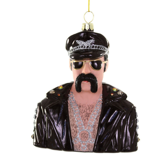 Decorative ornament of a man with a drooping black mustache and long sideburns wearing sunglasses, a black leather jacket, and a brimmed hat with silver chain accent. Heavy silver chain drapes over hairy chest. On a white background.