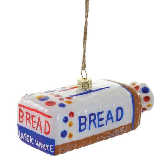 A blown glass Christmas ornament in the shape of a loaf of bread with the text 'bread' and the brand 'Wonder Bread' printed on it, with a gold cord loop for hanging. Blue, red, and yellow dots on bread label.