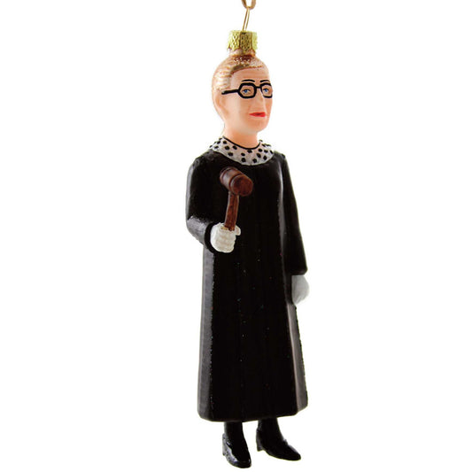 The judicial superstar Ruth Bader Ginsburg is depicted full length in a black robe, one of her iconic collars, or jabots, and carries a gavel in this glass ornament from Cody Foster.