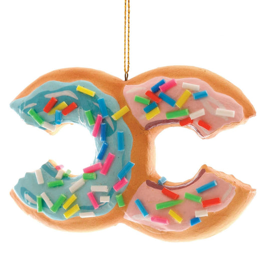 A blown glass donut ornament in the shape of the Chanel logo with hand-painted colorful details, designed to resemble a traditional donut with sprinkles on top. The ornament is sold with a cord loop for hanging.