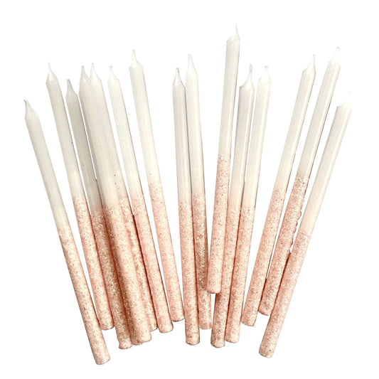long white candles with pink glitter covering the bottom half on a white background