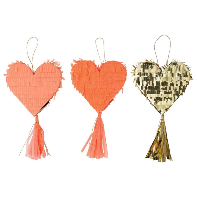Three small heart-shaped boxes finished with fringed tissue and finished with festive tassels on a white background
