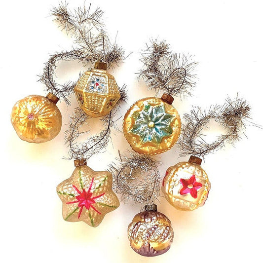 Decorative vintage-style ornaments with silver tinsel loops on a white background