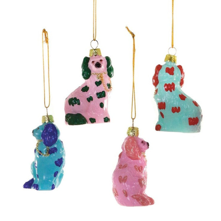 Four hanging dog ornaments in pastel colors with heart and spot patterns, suspended by gold strings on a white background.