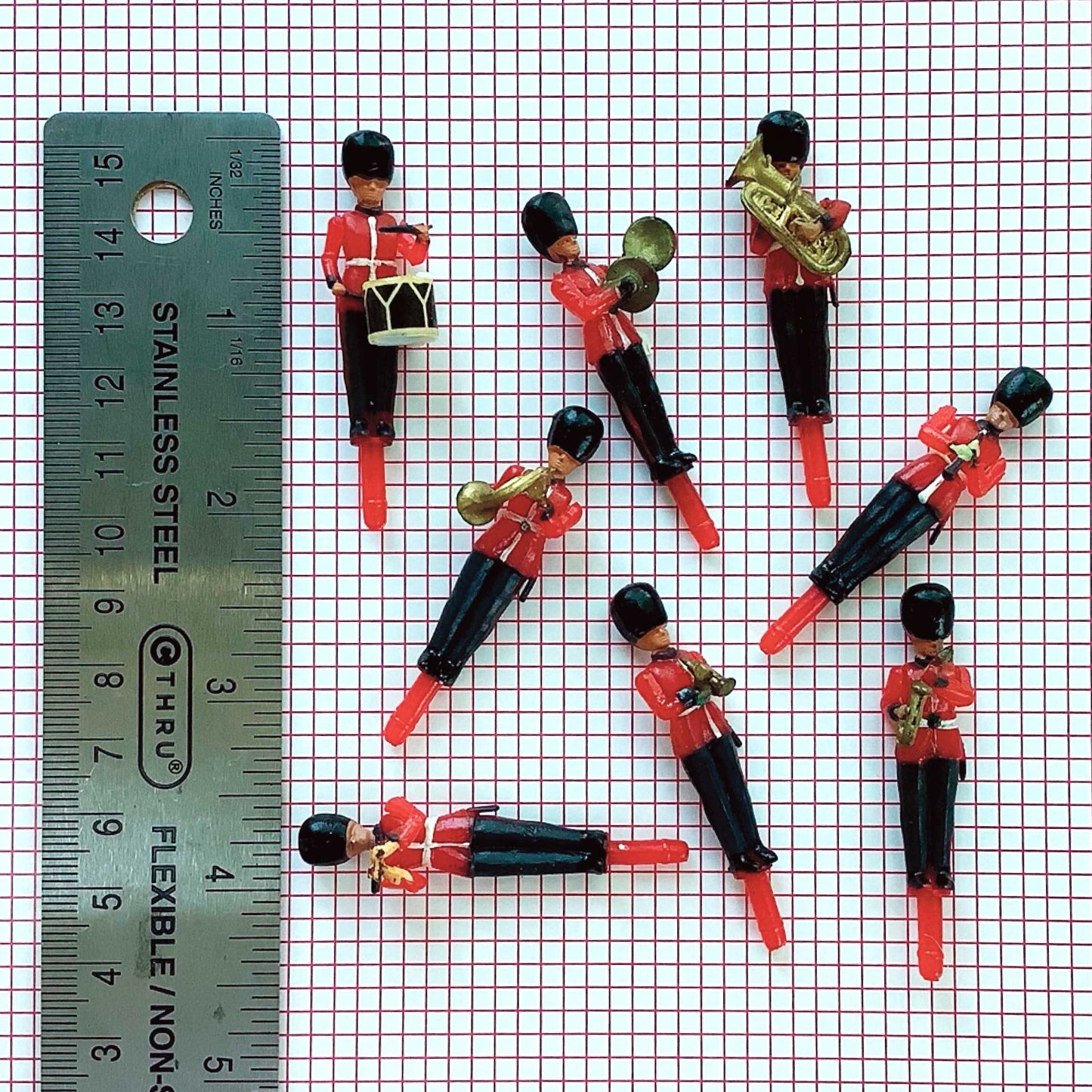 Small toy figures of musicians on a grid background with a ruler for scale.
