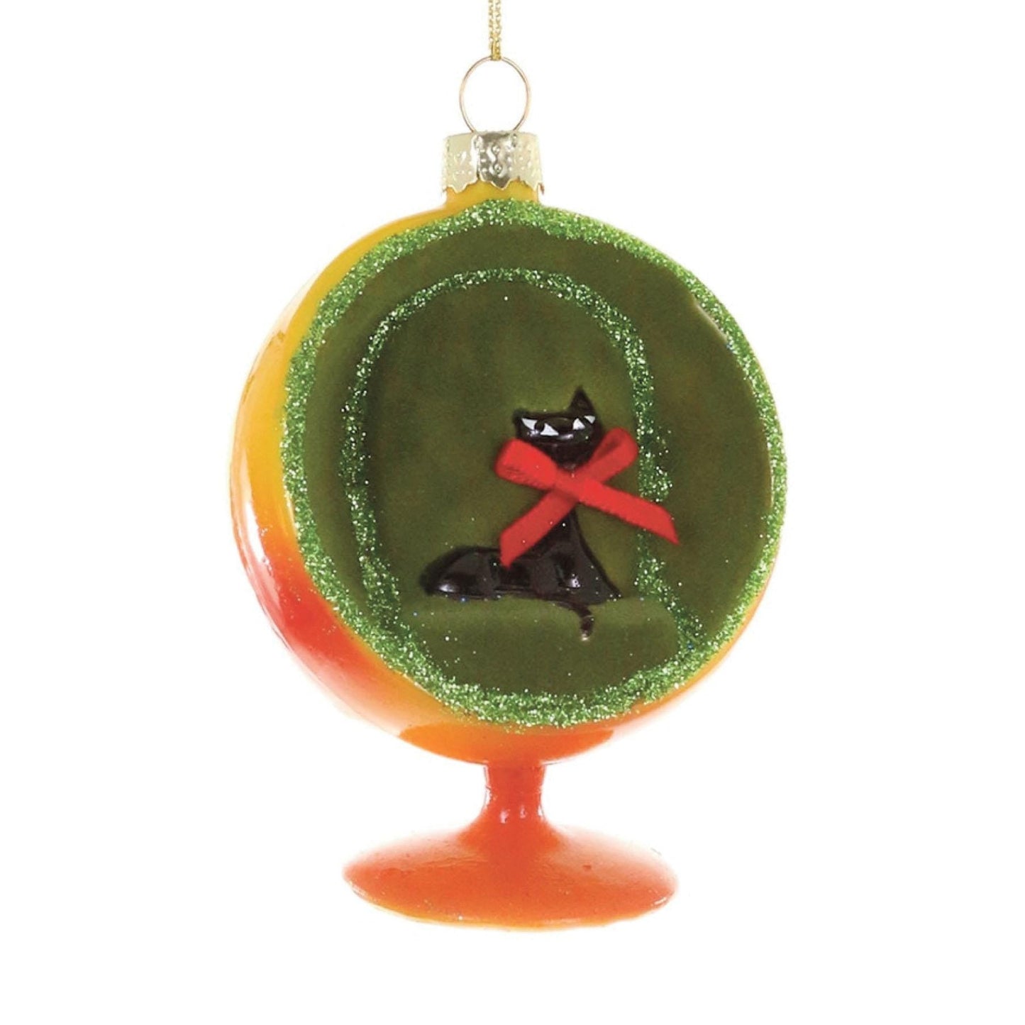 Decorative ornament with a black cat wearing a red satin bow and sitting inside a ball-shaped chair upholstered in green velvet and standing on an orange base.