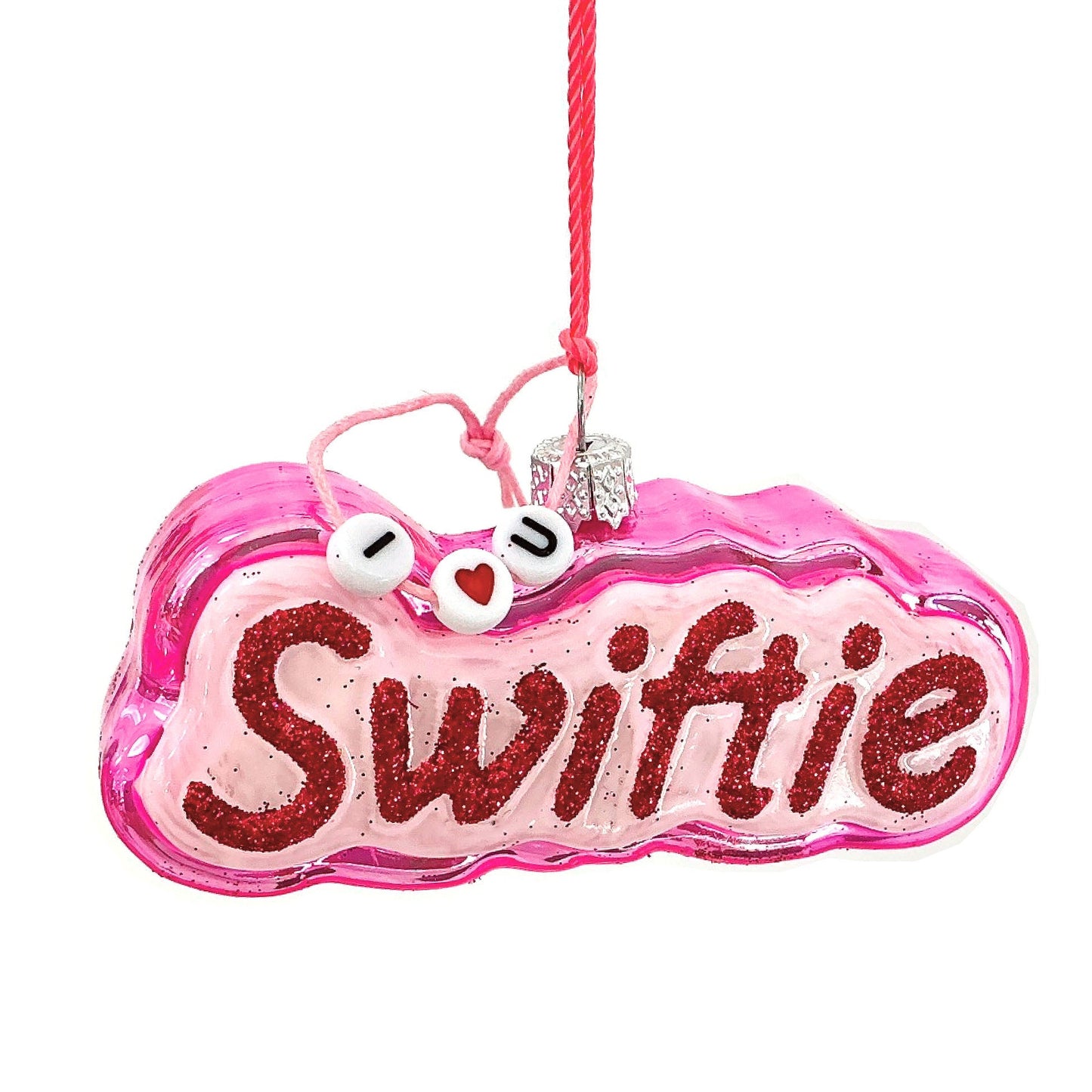 Hot pink ornament with glittery 'Swiftie' text on a white background, with a pink string holding beads that say I Love You around the ornament loop.